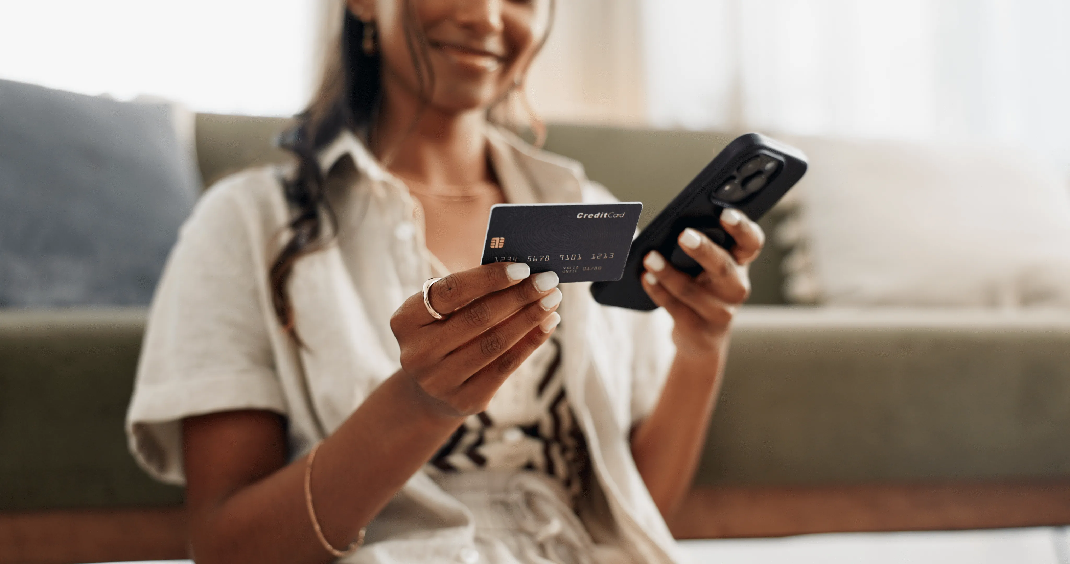 Woman smiling while inputting credit card info into mobile device